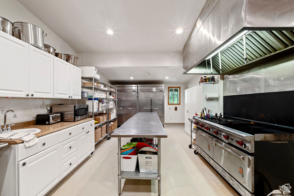 Kitchen with white cabinets, sink, and exhaust hood