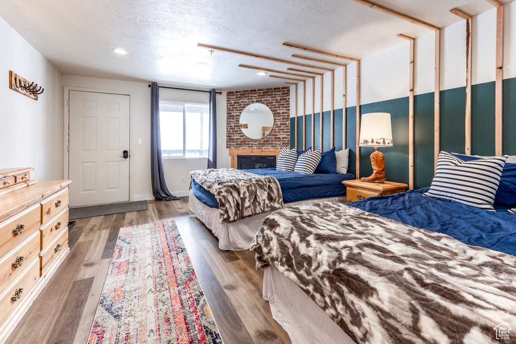 Bedroom featuring a brick fireplace, hardwood / wood-style flooring, and a textured ceiling