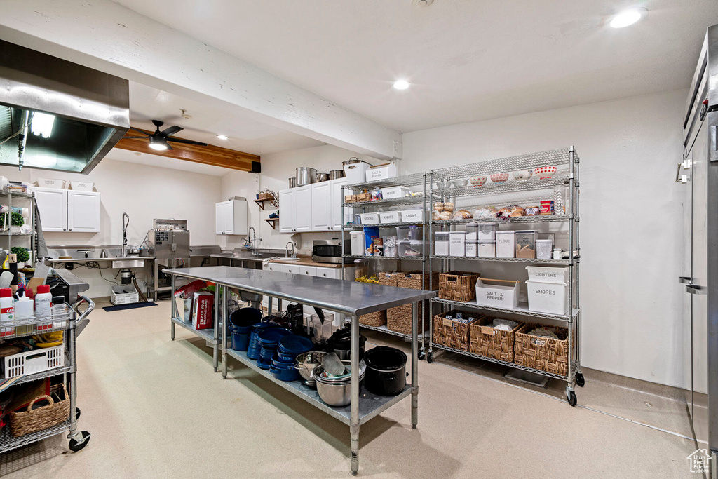 Kitchen with white cabinetry, light colored carpet, ceiling fan, and beam ceiling