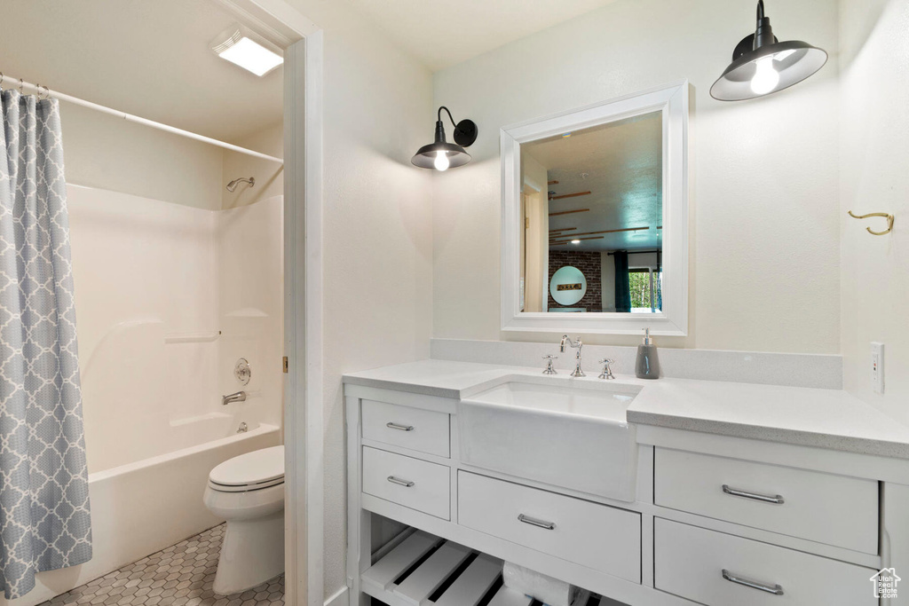 Full bathroom with shower / bath combo with shower curtain, tile patterned flooring, vanity, and toilet