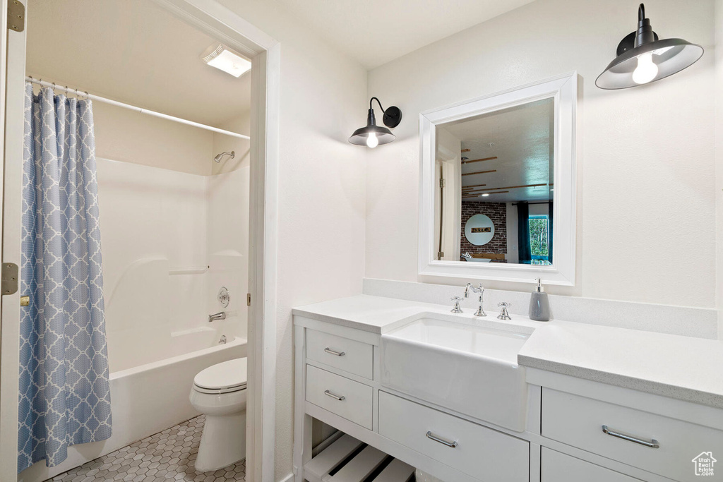 Full bathroom with toilet, vanity, tile patterned floors, and shower / bathtub combination with curtain