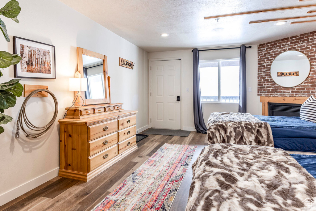 Bedroom with a textured ceiling, dark hardwood / wood-style floors, and a fireplace