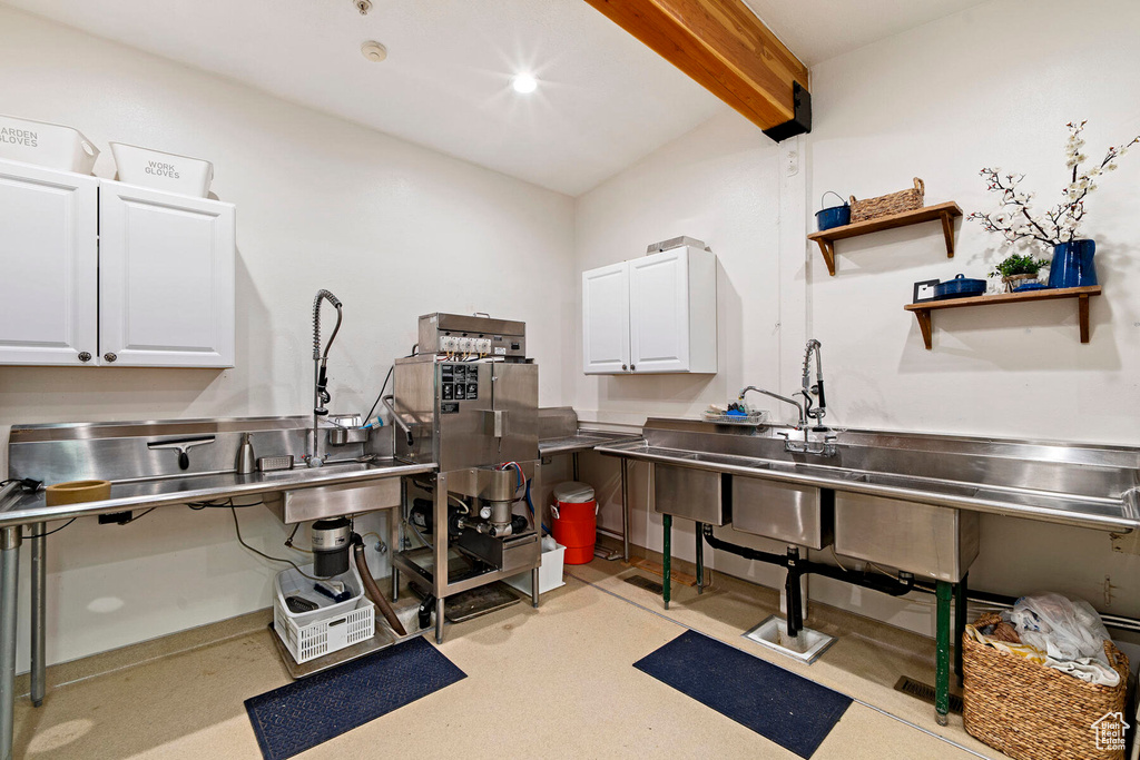 Kitchen with white cabinets, beamed ceiling, and stainless steel counters