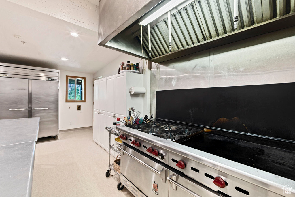 Kitchen featuring lofted ceiling, light colored carpet, stainless steel fridge, and white cabinets