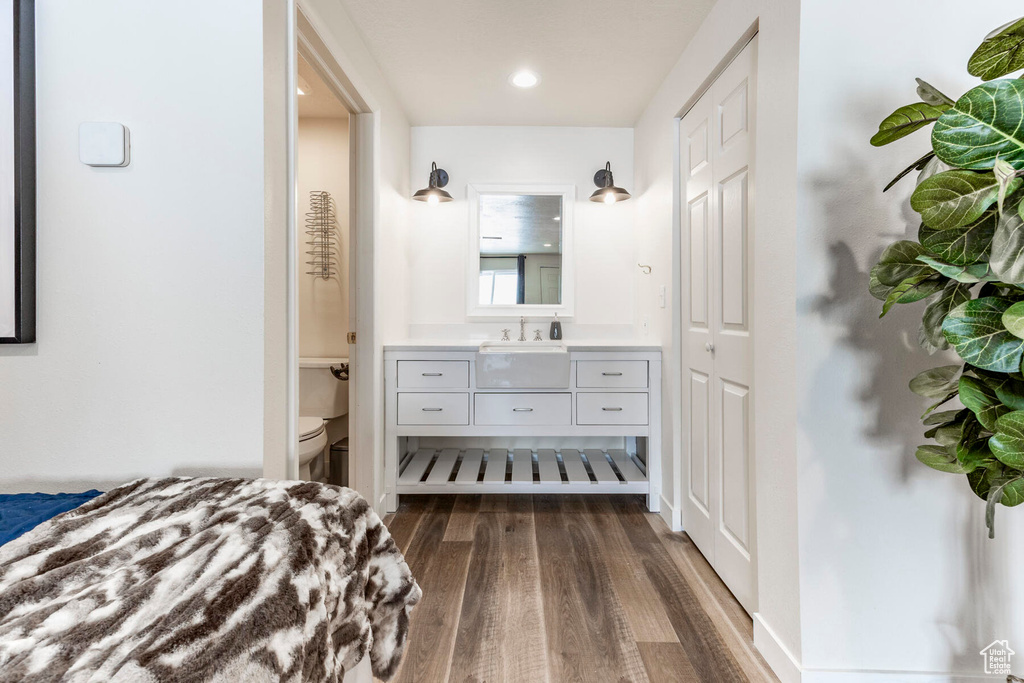 Unfurnished bedroom with ensuite bathroom, dark wood-type flooring, and sink