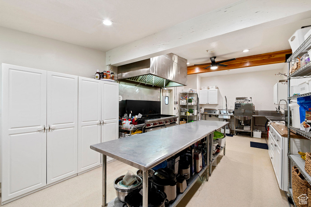 Kitchen with island range hood, white cabinets, light carpet, ceiling fan, and high end stainless steel range