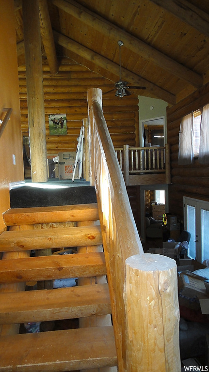 Stairs with wood ceiling, log walls, ceiling fan, and lofted ceiling with beams