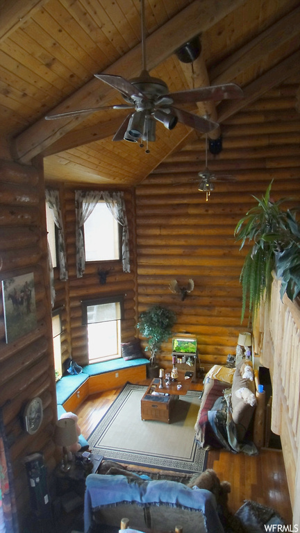 Interior space featuring wood ceiling, log walls, and ceiling fan