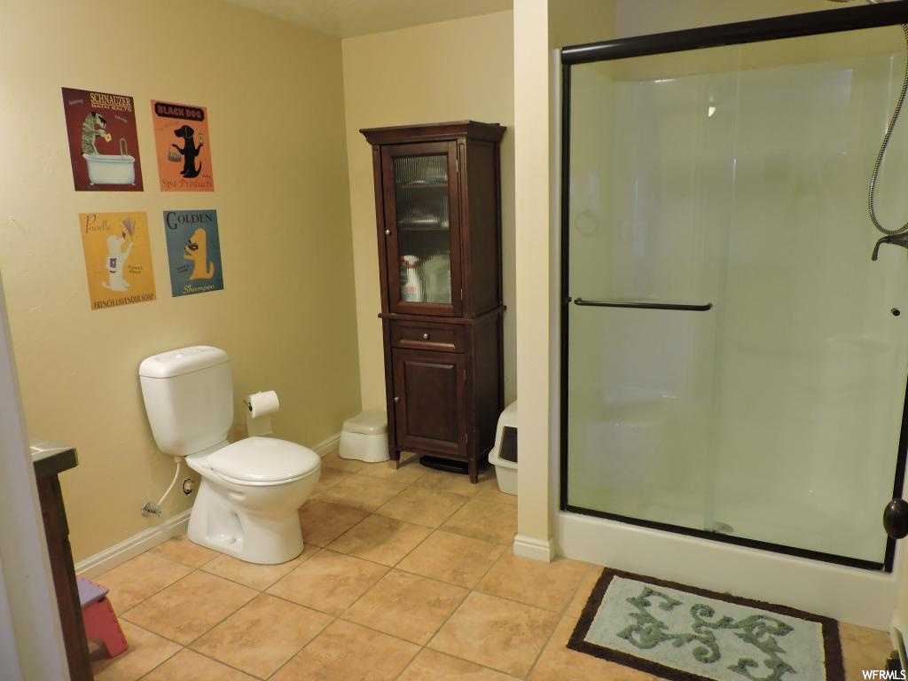 Bathroom with a shower with door, vanity, tile floors, and toilet