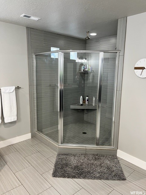 Bathroom featuring tile floors, a shower with shower door, and a textured ceiling