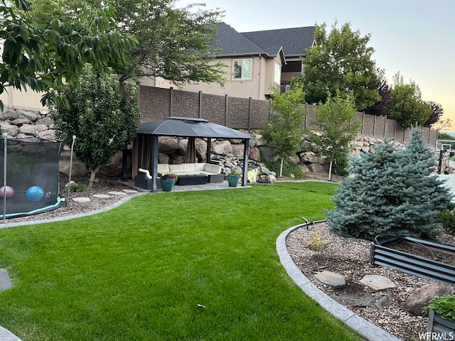 Yard at dusk with an outdoor hangout area and a gazebo