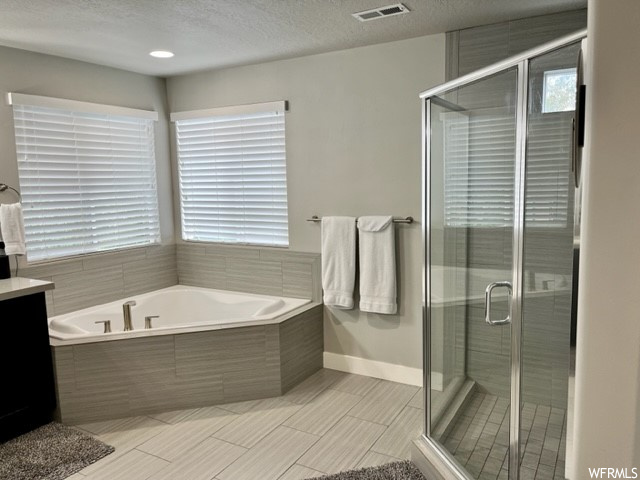 Bathroom with shower with separate bathtub, tile floors, vanity, and a textured ceiling