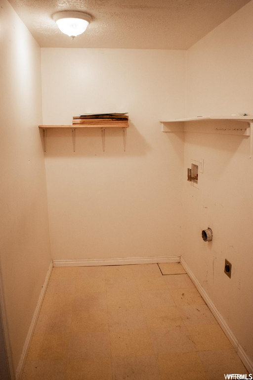 Laundry area with a textured ceiling, hookup for a washing machine, electric dryer hookup, and light tile floors