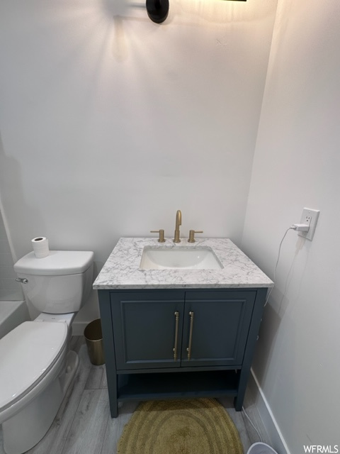 Full bathroom featuring wood-type flooring, toilet, vanity, and shower / washtub combination