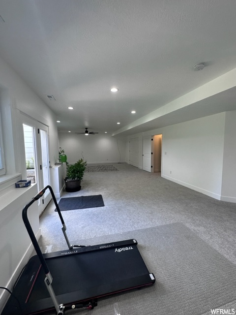 Workout room with ceiling fan and light colored carpet