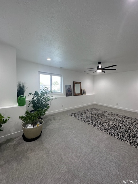 Interior space with carpet floors, ceiling fan, and a textured ceiling