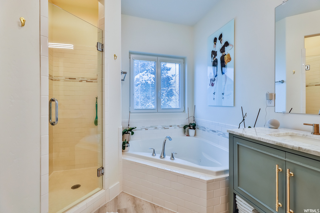 Bathroom with independent shower and bath, vanity with extensive cabinet space, and wood-type flooring