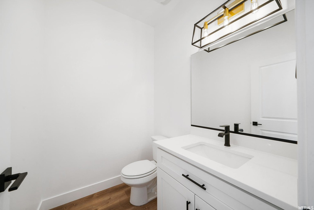 Bathroom with light hardwood flooring, mirror, and vanity