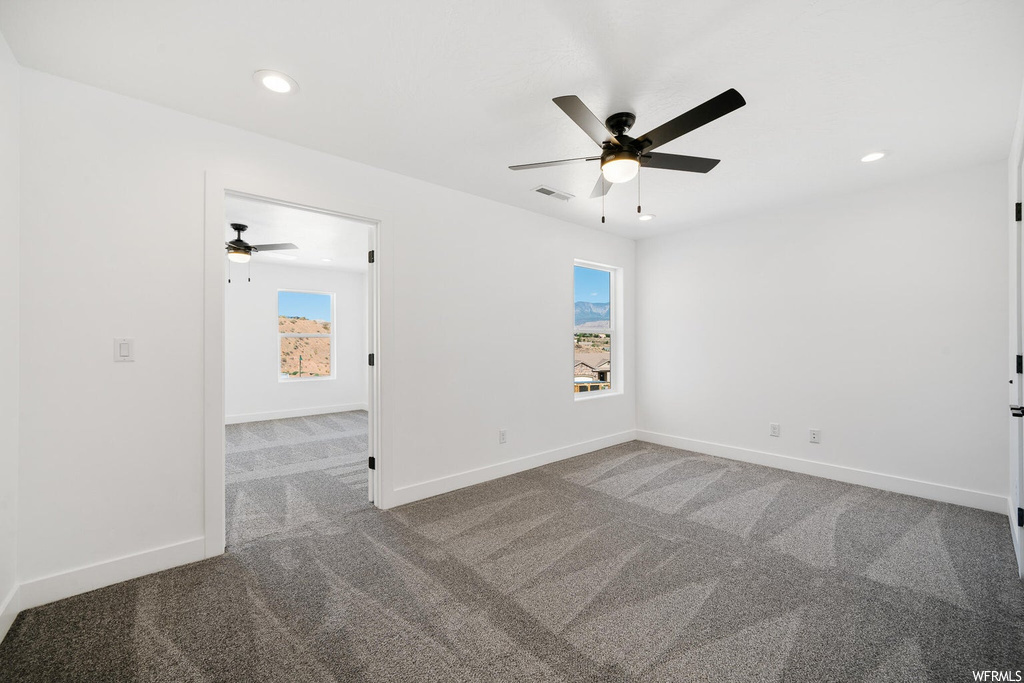 Spare room with light carpet, a healthy amount of sunlight, and ceiling fan