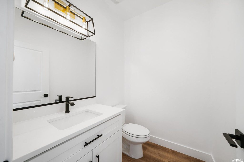 Bathroom with hardwood flooring, vanity with extensive cabinet space, and mirror