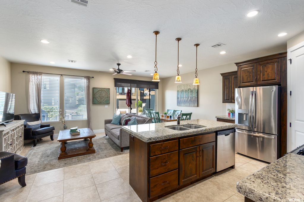 Kitchen with sink, ceiling fan, pendant lighting, a kitchen island with sink, and stainless steel appliances