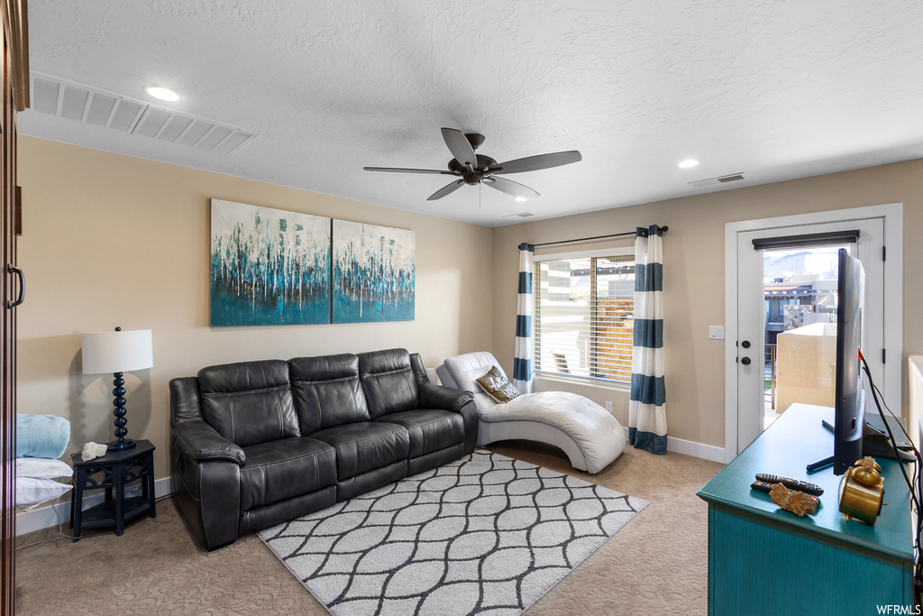 Carpeted living room featuring ceiling fan