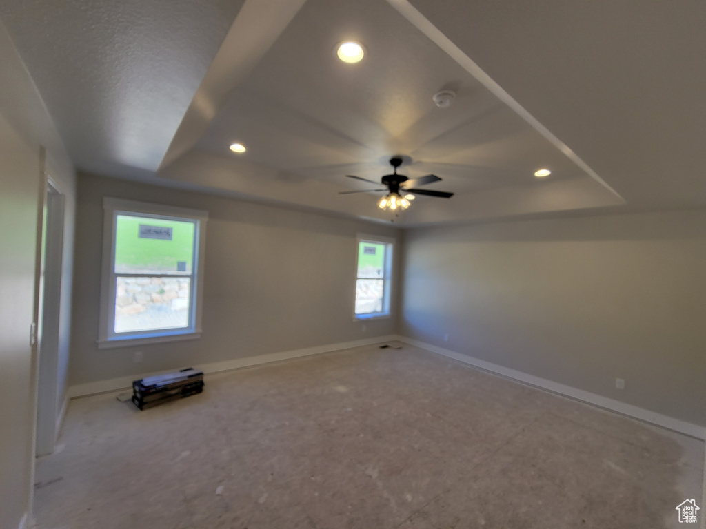 Empty room featuring a raised ceiling and ceiling fan