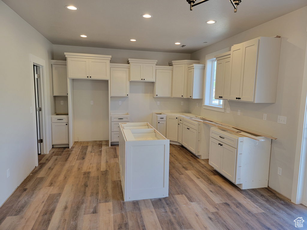 Kitchen featuring light hardwood / wood-style flooring, a center island, and white cabinetry