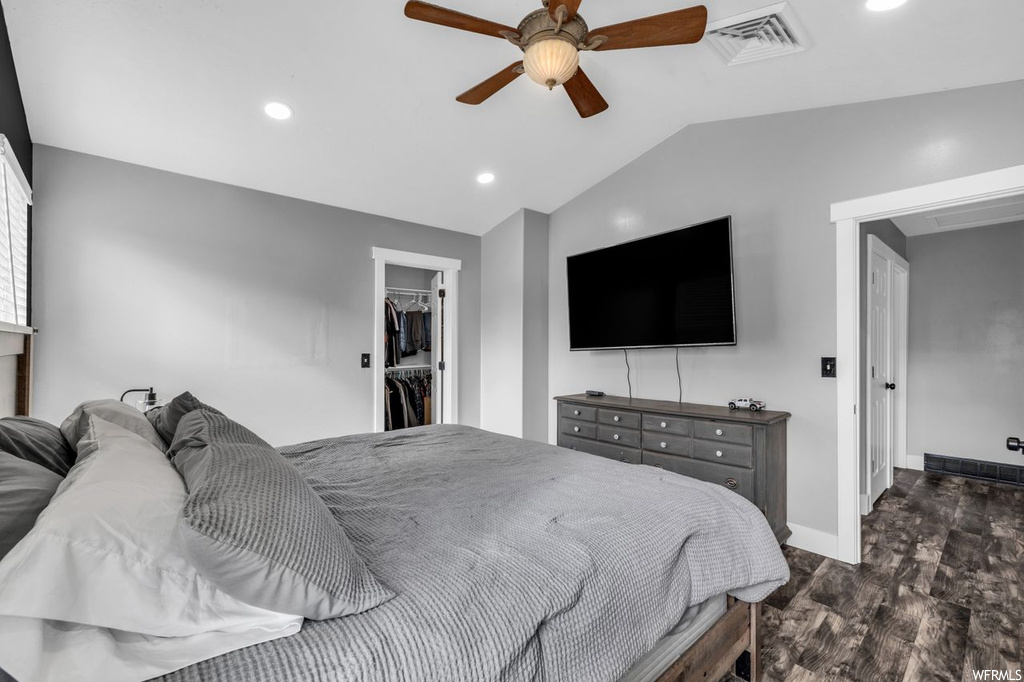 Bedroom featuring dark hardwood flooring, a spacious closet, a closet, vaulted ceiling, and ceiling fan