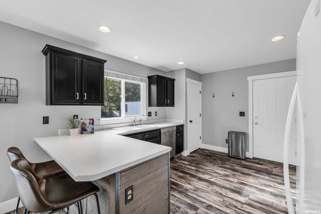 Kitchen featuring dishwasher, white refrigerator, a kitchen bar, dark hardwood floors, and kitchen peninsula
