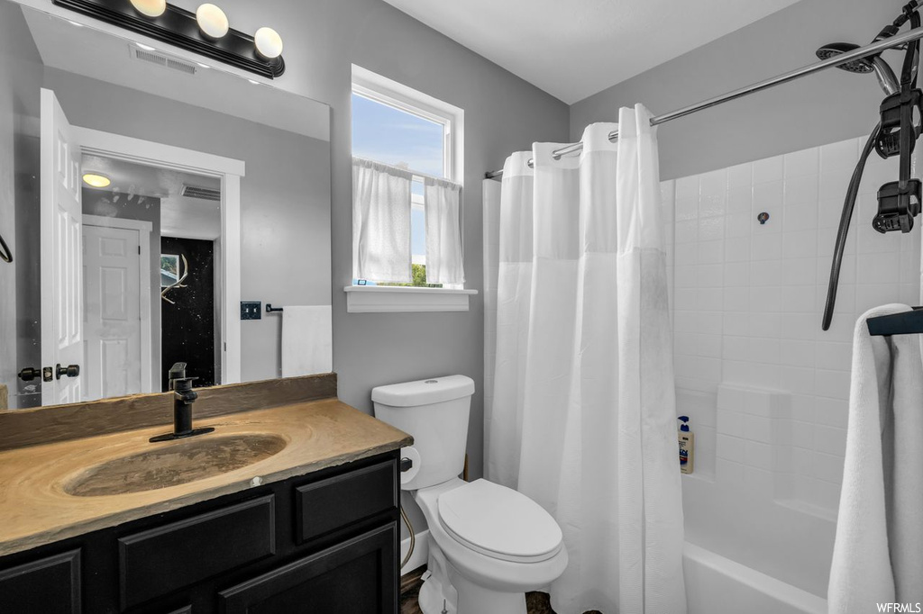 Full bathroom with toilet, vanity, and shower / bath combination with curtain
