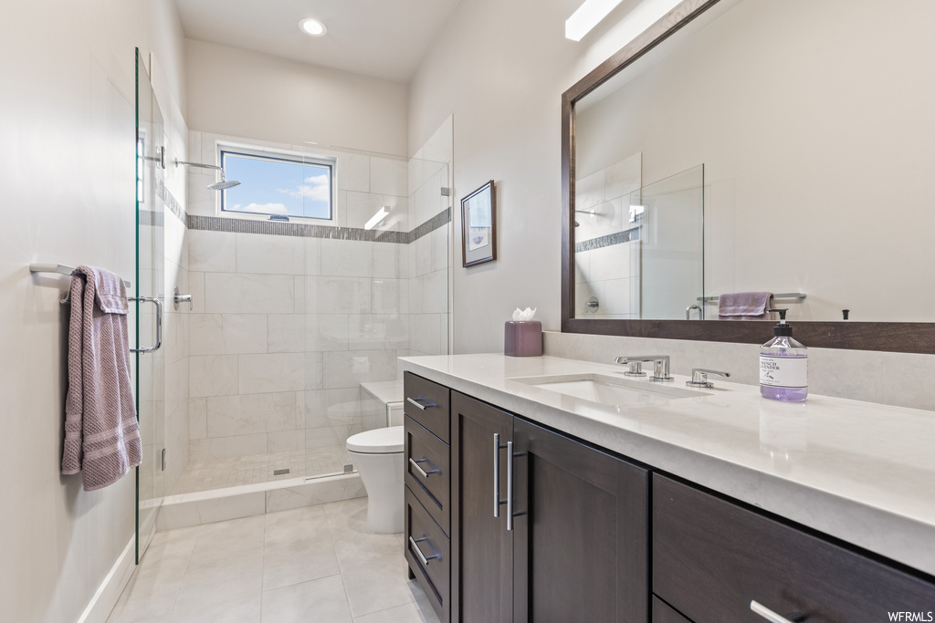 Bathroom featuring oversized vanity, light tile flooring, mirror, and a shower with shower door