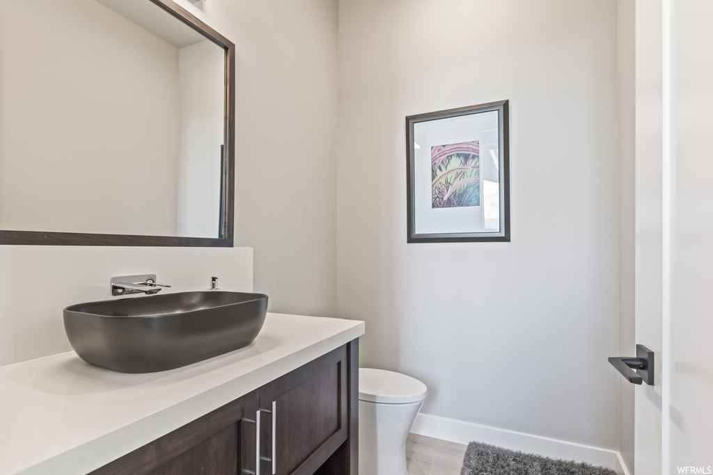 Bathroom with light hardwood flooring, mirror, and vanity