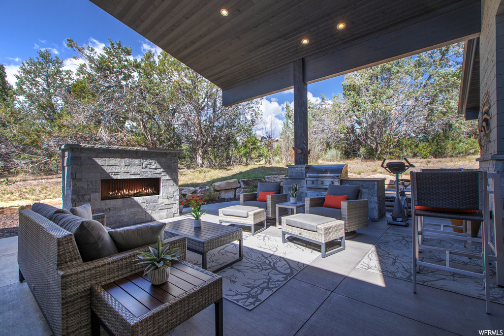 View of terrace featuring an outdoor fireplace and an outdoor kitchen