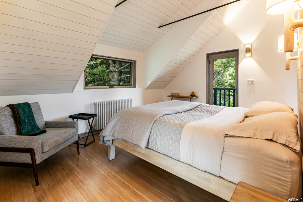 Hardwood floored bedroom with radiator heating unit, wooden ceiling, and vaulted ceiling