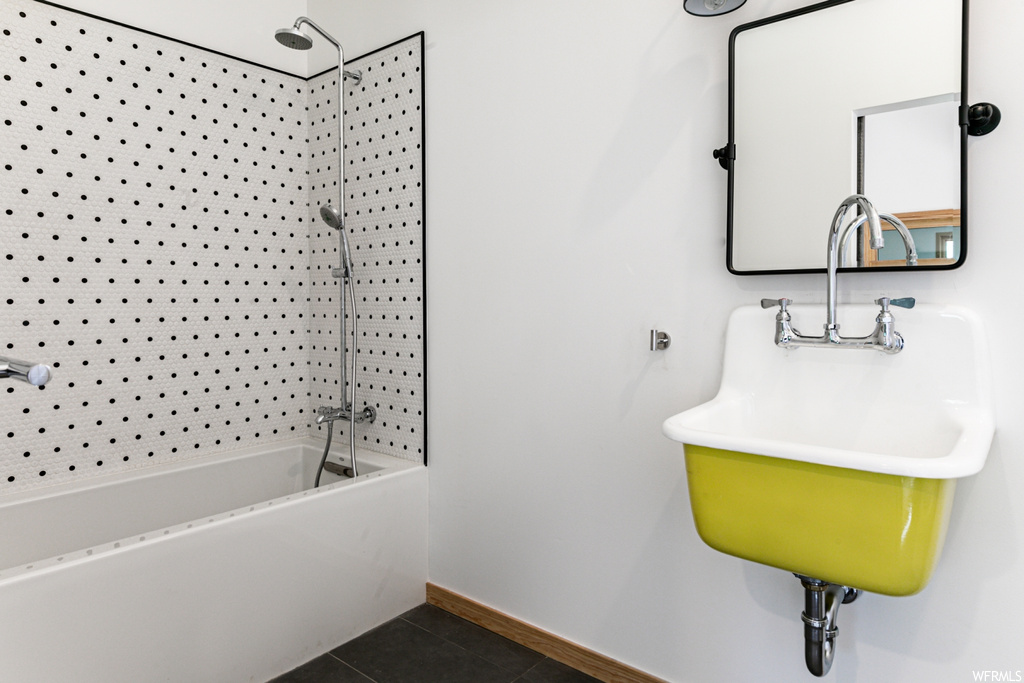 Bathroom featuring shower / washtub combination, mirror, sink, and light tile floors