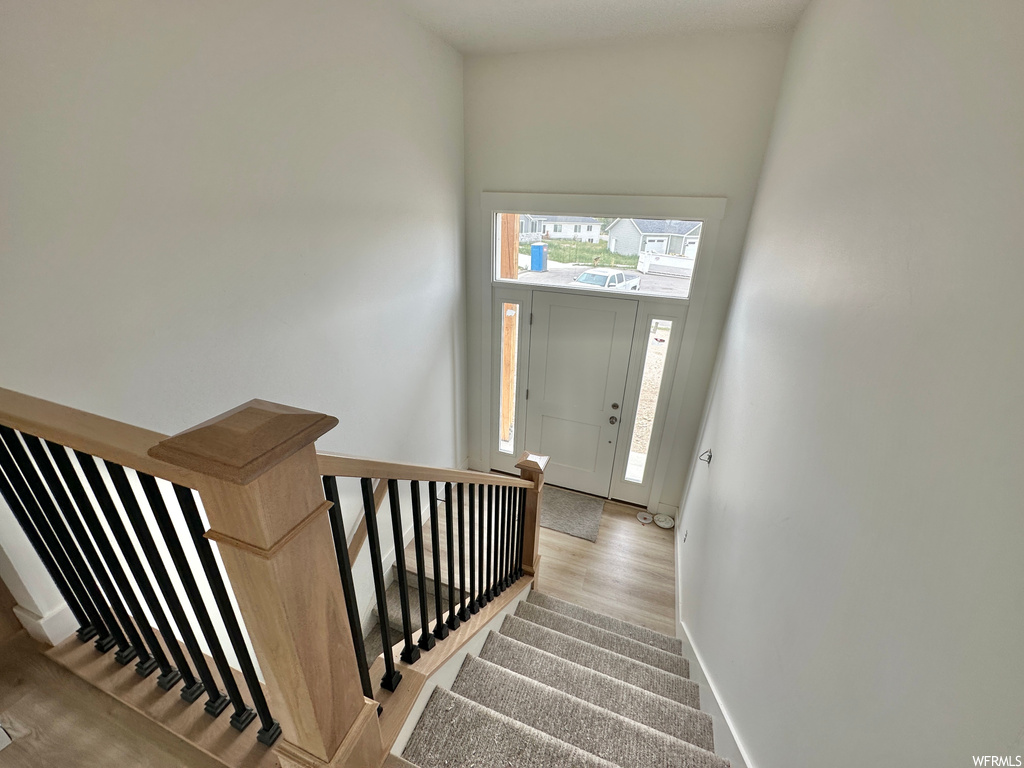 Stairs featuring a towering ceiling and light hardwood flooring