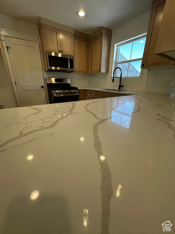 Kitchen featuring sink, tasteful backsplash, stainless steel appliances, and light stone countertops