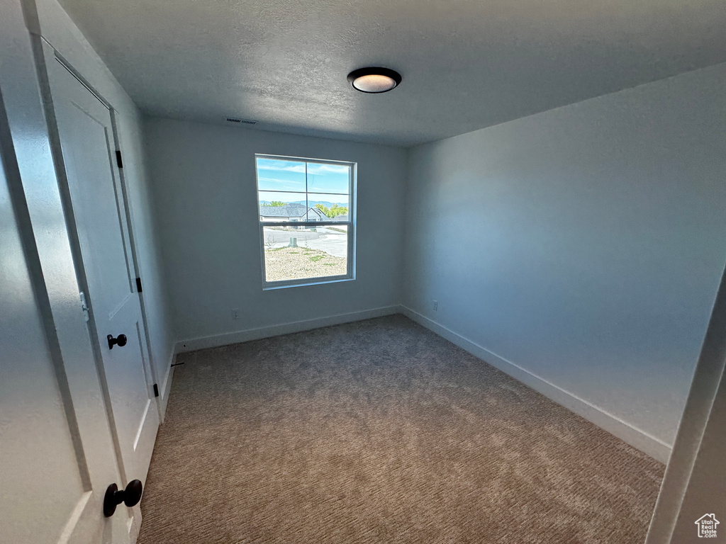 Carpeted empty room featuring a textured ceiling