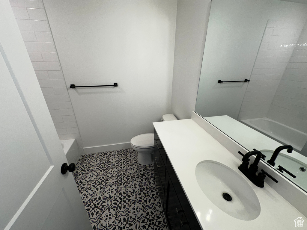 Full bathroom featuring oversized vanity, toilet, tile floors, and tiled shower / bath combo