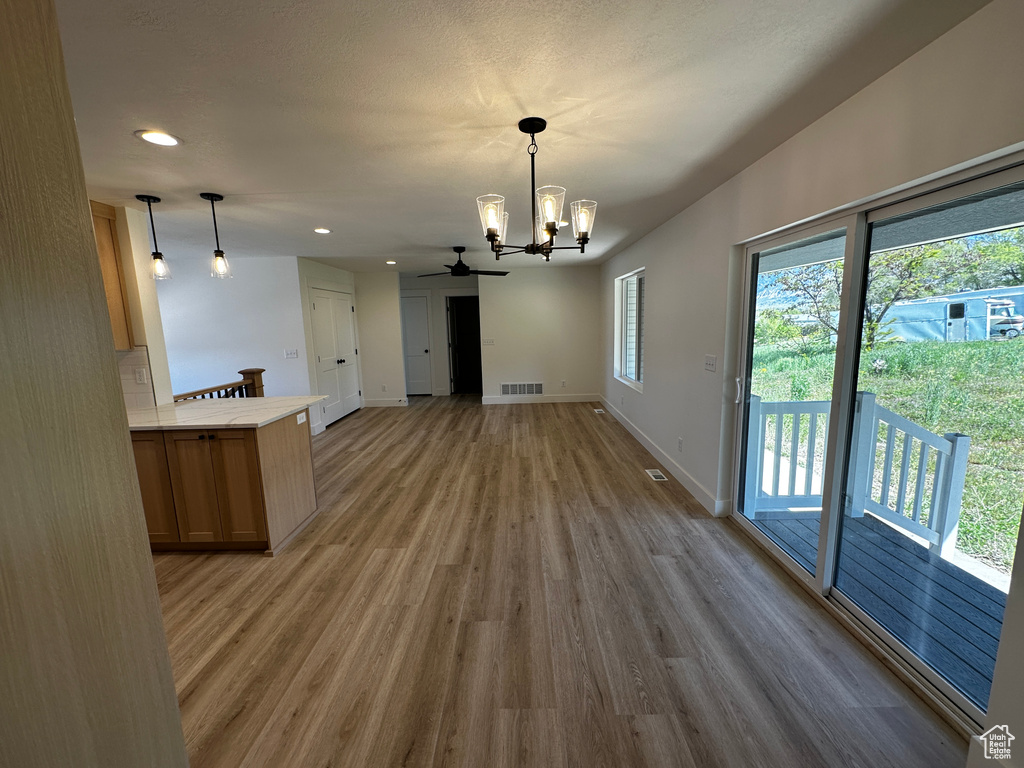 Interior space featuring wood-type flooring and ceiling fan with notable chandelier