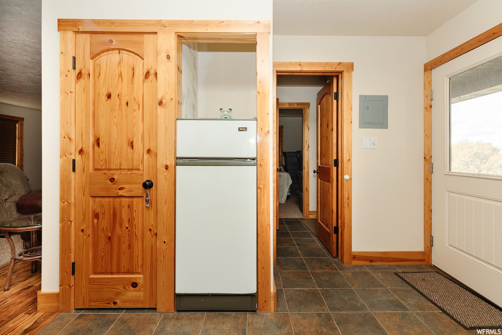 Kitchen with white fridge and dark tile flooring