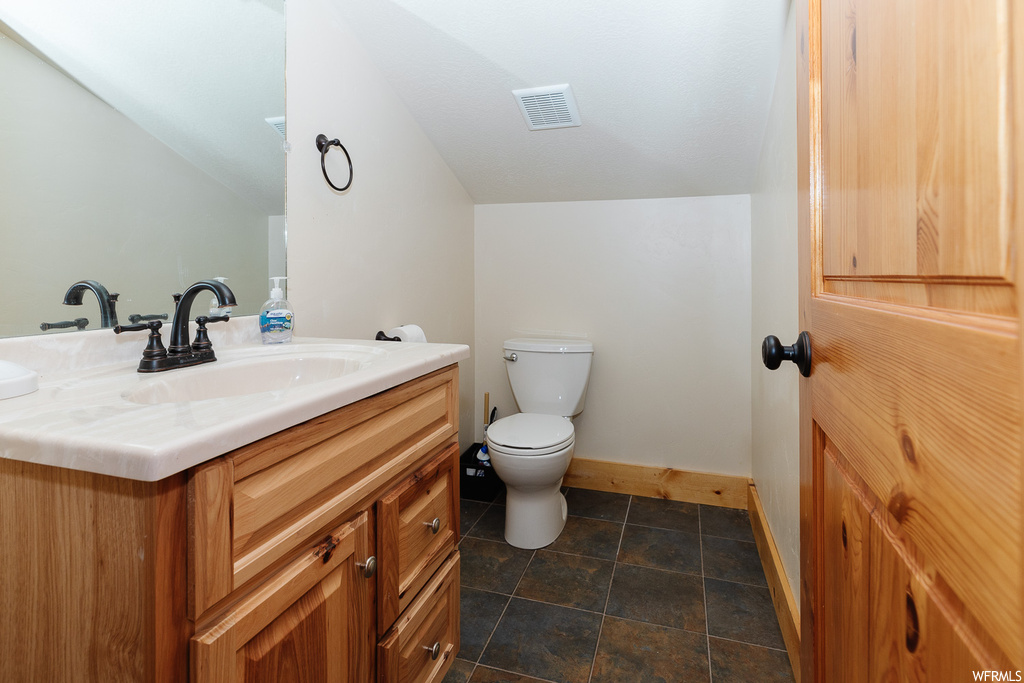 Bathroom with lofted ceiling, tile flooring, oversized vanity, and toilet