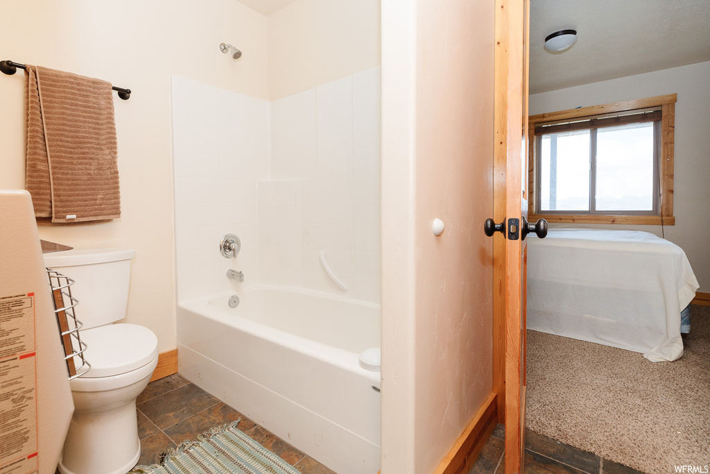 Bathroom featuring toilet, bathtub / shower combination, and tile flooring