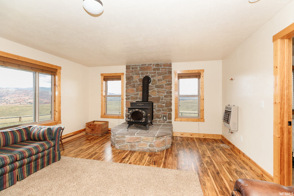 Living room featuring hardwood flooring, a wall mounted air conditioner, and a wood stove