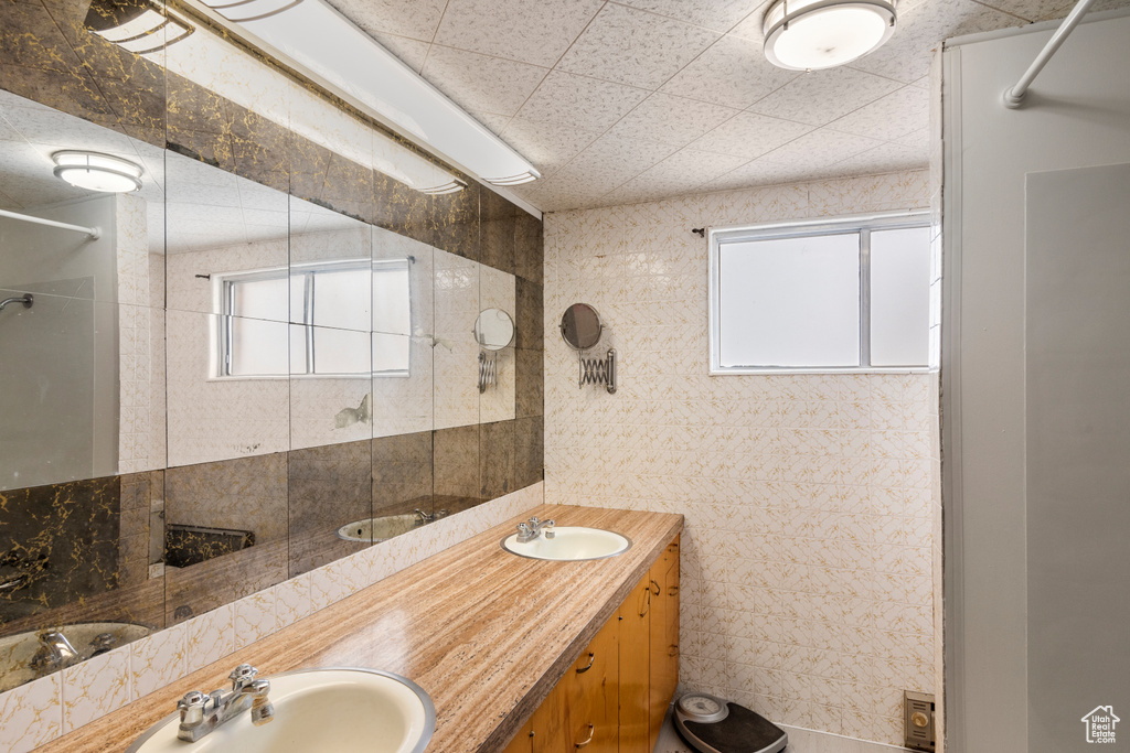 Bathroom featuring double vanity and tile walls