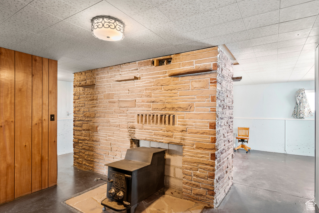 Interior space featuring a wood stove, wood walls, and concrete floors