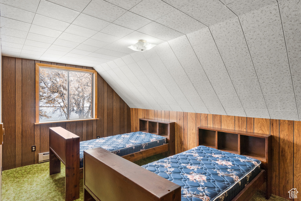Carpeted bedroom with wood walls, lofted ceiling, and a baseboard heating unit