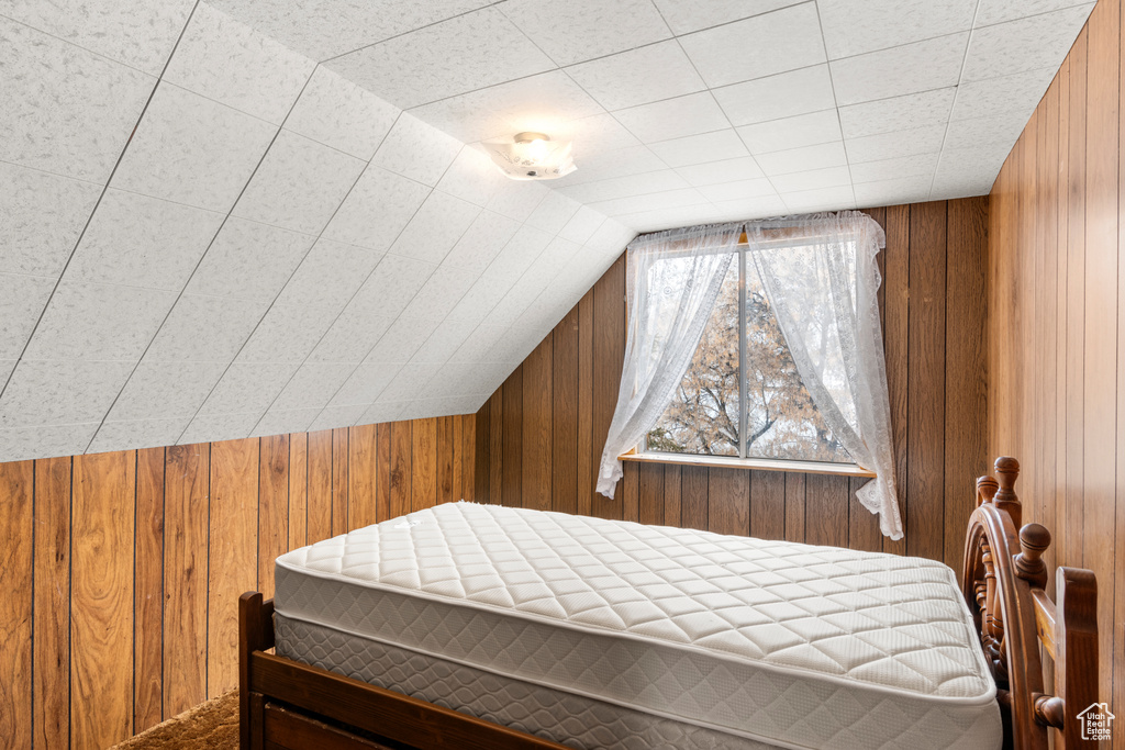 Bedroom featuring vaulted ceiling and wooden walls