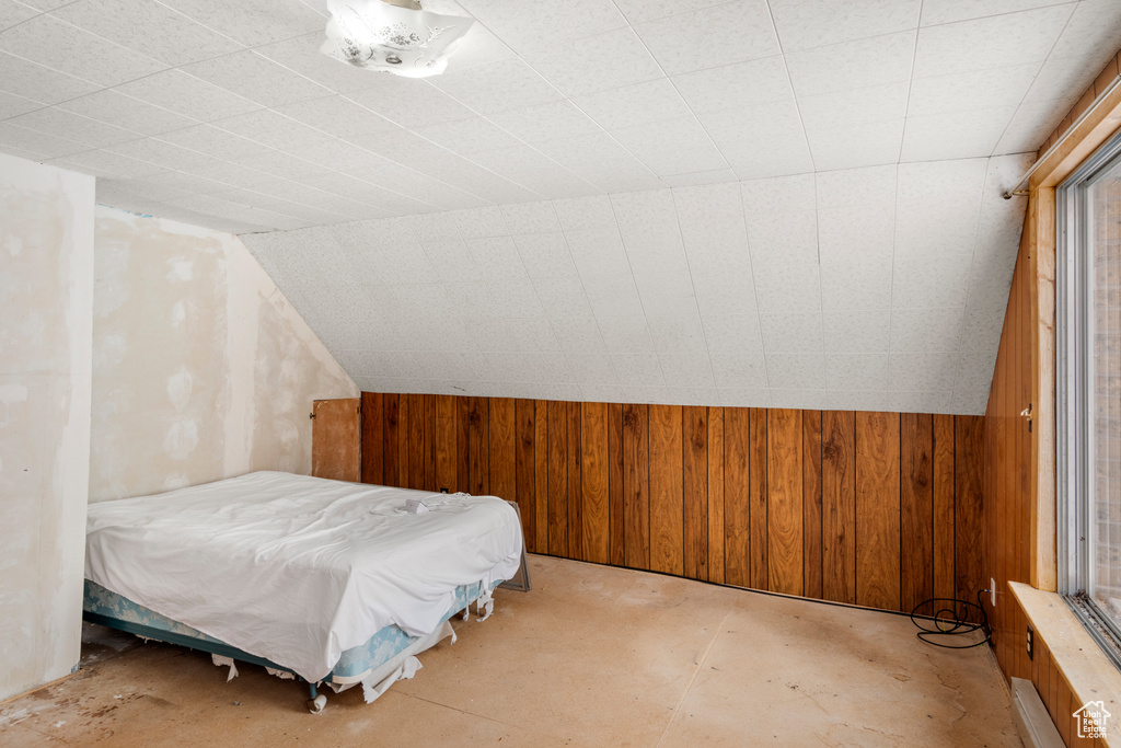 Bedroom with vaulted ceiling and wooden walls